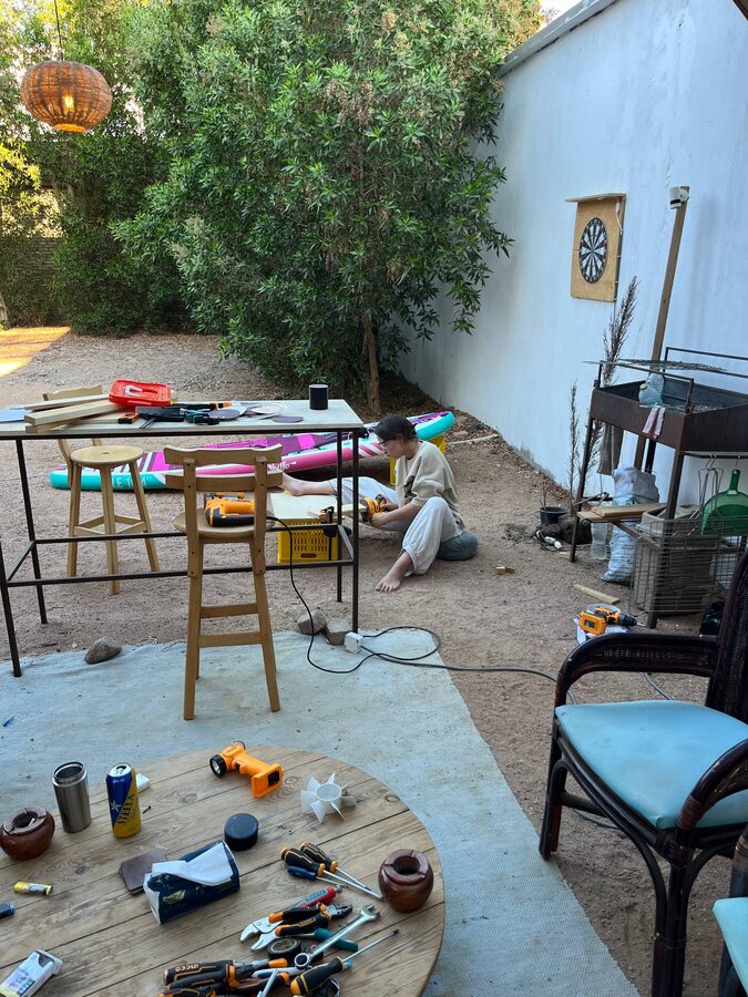 Improvised outdoor workshop in a courtyard: jigsaw on the ground, tool table, offcuts