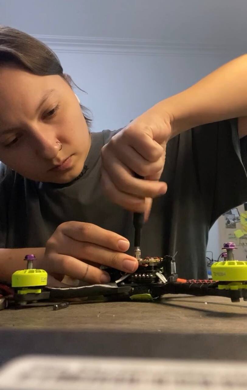 Annie fastening a motor on an FPV drone at her workbench