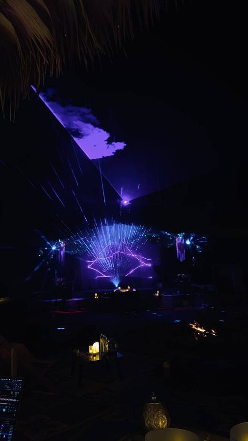 Laser fan and beam over the stage at night, haze and candles