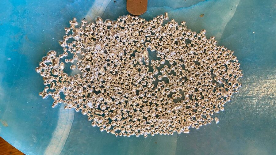 Pile of silver casting grain on a blue stone slab